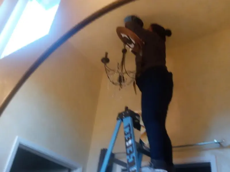 Electrician installing a chandelier in a Williams residence